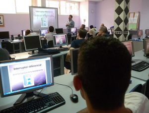 Vista general de un aula informática con los alumnos y el profesor en la pizarra digital